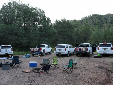 The vans with supplies parked around the camp site in a forest clearing. Image by Harry Tang