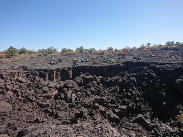 Students rest along a cliff-side in the volcanic flow