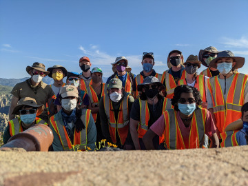 The group of ~17 people poses in their vests with the camera propped on a rock. Image by Robert Melikyan