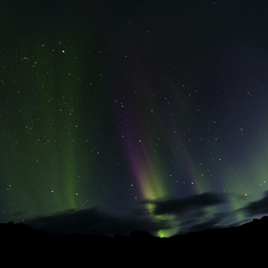 The Northern Lights (Aurora Borealis) are visible from Iceland and different colors are related to the ionization of different molecules in the atmosphere as solar wind is channelled toward the Earth's surface along magnetic field lines.