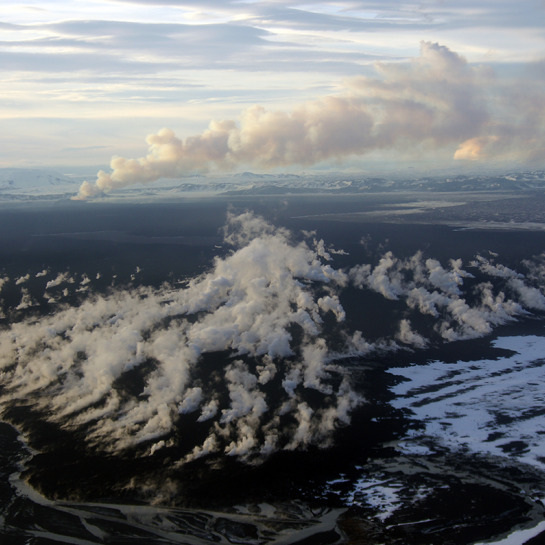 The distal (northern) margin of the active lava flow at Holuhraun observed from an aircraft on November18, 2014. The lava flow is entering the Jökulsá á Fjöllum river, creating hotsprings and fumeroles in the foreground. In the background a gaseous plume can be seen emerging from the vent.