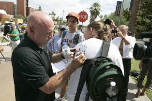Astronaut Mark Kelly signing a person's shirt.