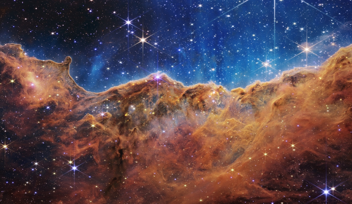 This landscape of what looks like mountains and valleys speckled with glittering stars is actually the edge of a nearby, young, star-forming region called NGC 3324 in the Carina Nebula. Captured in infrared light by NASA's Webb Telescope, this image reveals for the first time previously invisible areas of star birth. NASA, ESA, CSA, and STScI