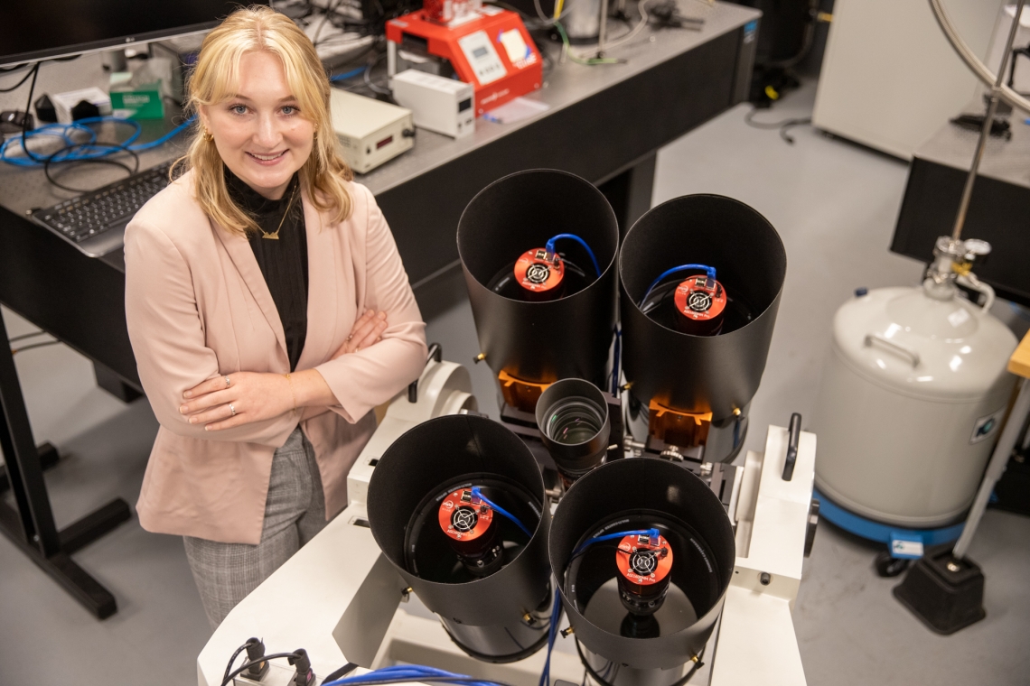 Grace Halferty, a senior graduating this summer with a bachelor's degree in aerospace and mechanical engineering and the paper's lead author, with the instrument researchers built to measure the brightness and position of SpaceX Starlink satellites.