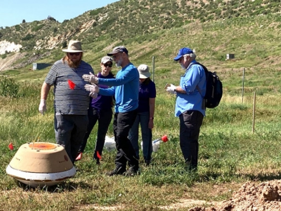 OSIRIS-REx mission members including UArizona scientists Dante Lauretta (center) and Anjani Polit (in back) practice procedures during an exercise with a replica of the spacecraft's sample capsule. The dirt pile on the right was used to simulate a muddy landing site in case of rain.