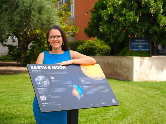 Zarah Brown, a doctoral student at the UArizona Lunar and Planetary Laboratory with sign depicting various Earth & Moon