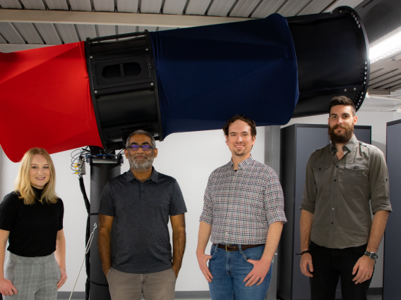 UArizona Space Domain Awareness team - including Grace Halferty, Vishnu Reddy, Adam Battle and Tanner Campbell - stand in front of the RAPTORS-1 telescope on top of Kuiper Space Sciences Building. 