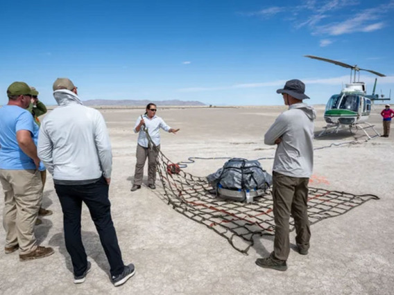 OSIRIS-REx team members practice getting a mock sample capsule packed for its helicopter flight