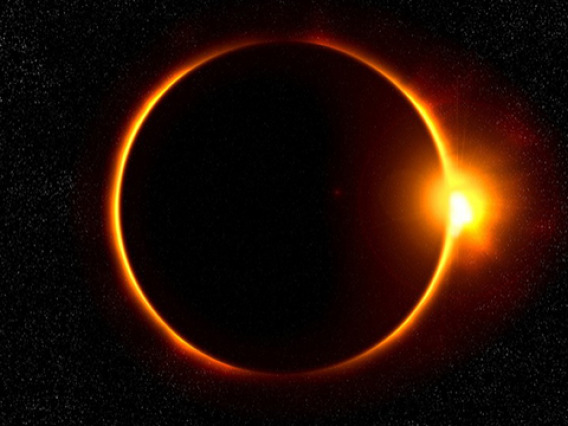 The sun is eclipsed by the moon against a starry background.