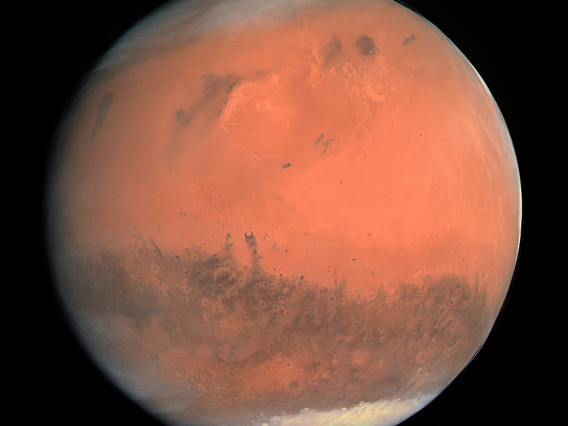 NASA image of Mars with a rusty red surface and icy polar caps at top and bottom.